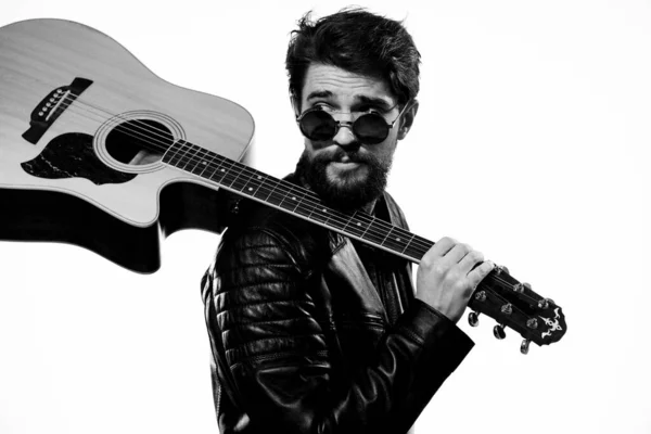 一个男人手里拿着一把吉他，音乐，情感，黑色皮夹克，墨镜工作室，浅色背景 — 图库照片