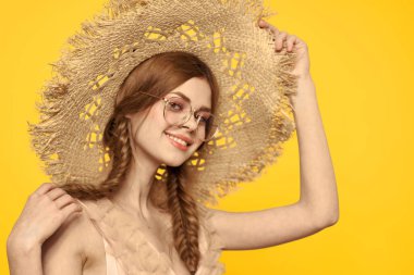 Saçları örgülü ve sarı arka planda şapkası olan güzel bir kadının portresi.