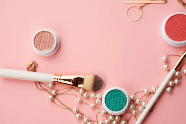 Escovas de maquiagem e cosméticos profissionais de sombra de olhos em fundo rosa — Fotografia de Stock