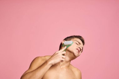 Elinde masaj aleti olan yakışıklı bir adam izole edilmiş pembe arka planda temiz bir cilt.