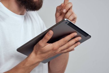 Açık arkaplanda dokunmatik ekranlı tablet erkek elleri beyaz tişört kırpılmış görünüm
