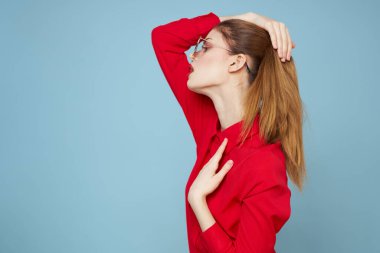 Mavi arka plandaki kırmızı gömlekli kadın yüz ve güneş gözlüklü kırmızı dudak makyajı modeli ile el ele tutuşuyor.