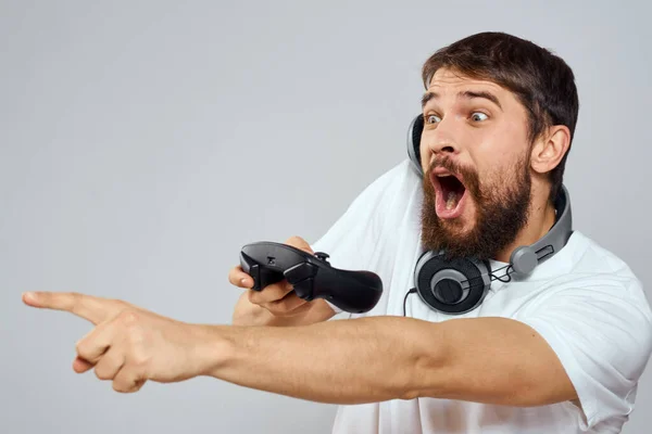Hombre con auriculares gamepad jugando tecnología de ocio blanco camiseta fondo claro —  Fotos de Stock