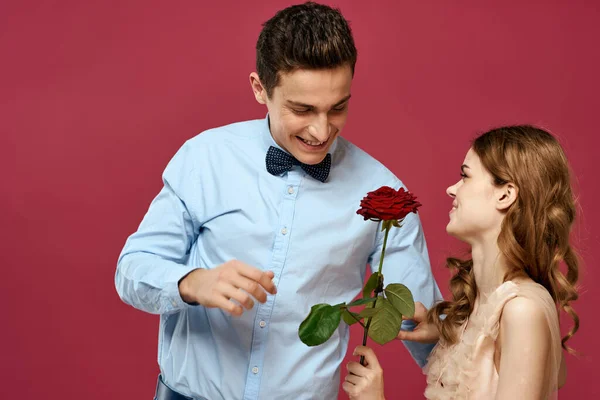 Szerelmes férfi és nő egy piros virág egy rózsaszín háttér ölelés egymást másolás tér — Stock Fotó