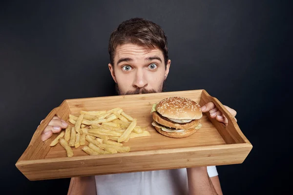 Emotionaler Mann mit Holzpalette Fast Food Hamburger Pommes Frites Essen Food Lifestyle dunkler Hintergrund — Stockfoto