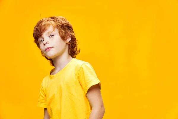 Tシャツに興味のある顔の表情で彼の手で陽気な赤髪の少年ジェスチャー — ストック写真