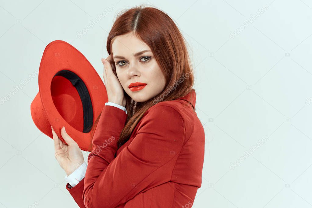 Elegant woman in red jacket hat holding long hair cropped light background