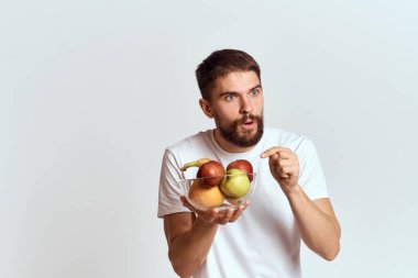 Elinde cam bardakta taze meyve taşıyan bir adam. Elleriyle jestler, vitaminler, sağlık enerjisi, sakallı bir adam.