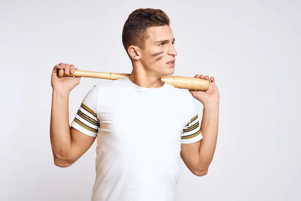 Un hombre con un bate de béisbol en un fondo ligero ejercicios patadas modelo de pelota deportiva —  Fotos de Stock