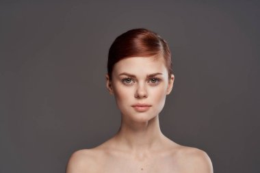 Güzel bir kadın çıplak omuzlar kozmetik temiz cilt cazibesi gri arka plan stüdyosu