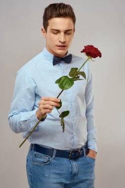 Kırmızı güllü ve açık renk gömlekli yakışıklı bir adamın portresi.