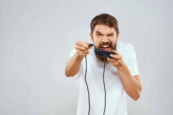 Un hombre con un mando en sus manos jugando juegos ocio estilo de vida tecnología blanco camiseta fondo claro —  Fotos de Stock