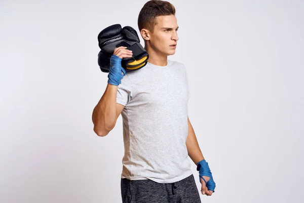 Homem forte com luvas de boxe e em uma camiseta branca em um fundo isolado vista cortada do modelo — Fotografia de Stock