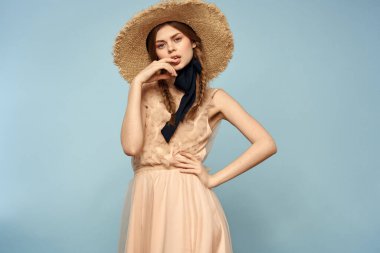 Mavi arka planda pembe elbiseli bir kız elleriyle romantik modeller yapıyor.