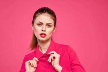 Pembe tişörtlü çekici bir kız parlak makyajlı kırmızı dudaklar ellerle işaret ediyor Boşluğu kopyala