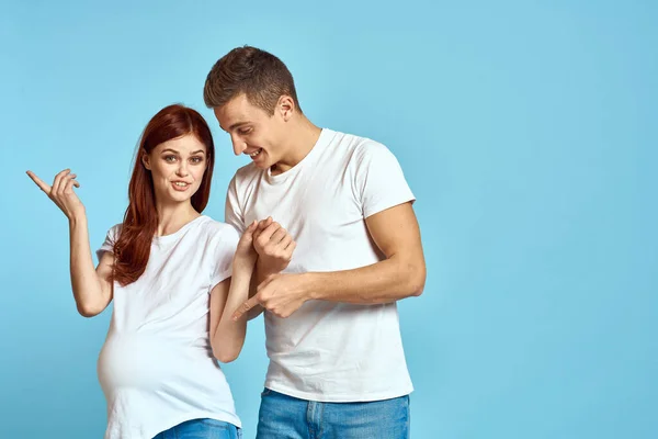 Zwangere vrouw in wit t-shirt en man getrouwd stel wachten op baby blauwe achtergrond bijgesneden weergave van emoties — Stockfoto