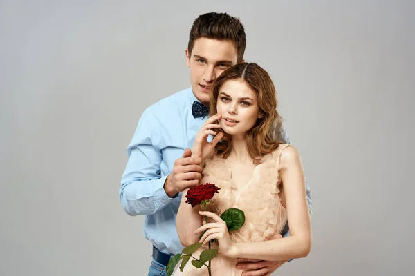 Fiatal pár ölelés romantika társkereső életmód kapcsolat fény háttér piros rózsa — Stock Fotó