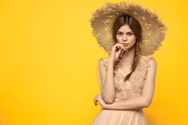 Hasır şapkalı duygusal kız ve sarı arka planda kırmızı örgülü bir elbise.