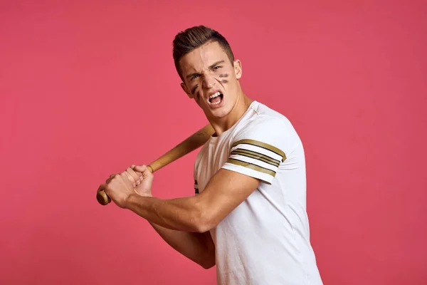 Un hombre con un bate en la mano juega béisbol sobre un fondo rosa con una camiseta blanca vista recortada —  Fotos de Stock