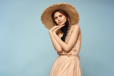 Mavi arka planda pembe elbiseli bir kız elleriyle romantik modeller yapıyor.