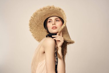 Bej elbiseli, hasır şapkalı, siyah kurdele takmış, manken görünümlü romantik bir kız.