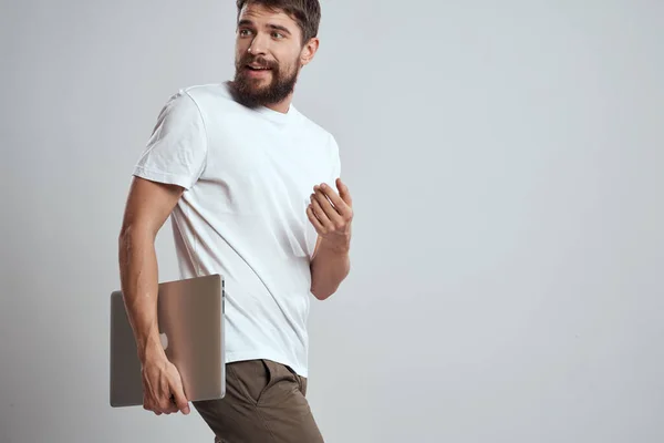 Чоловік з ноутбуком в руках на світлому тлі в білій футболці емоції світлого фону нові технології — стокове фото
