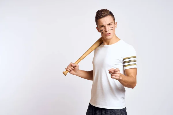 Un hombre con un bate de béisbol en un fondo ligero ejercicios patadas modelo de pelota deportiva —  Fotos de Stock