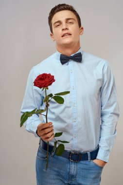 Kırmızı gül ve açık renk pantolon giyen romantik bir adam.