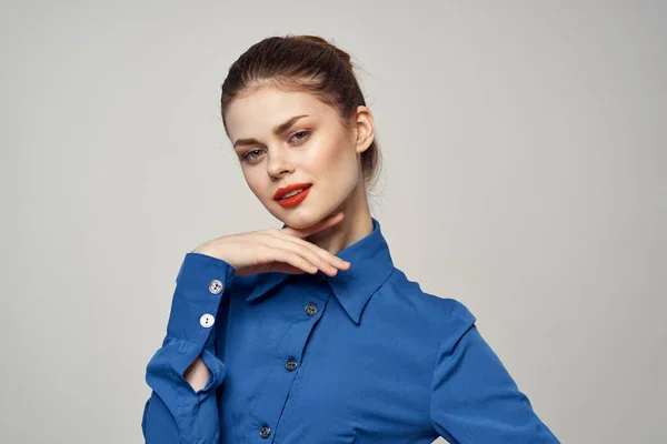 Una elegante dama de camisa azul hace gestos con las manos sobre un fondo claro y un retrato de primer plano — Foto de Stock
