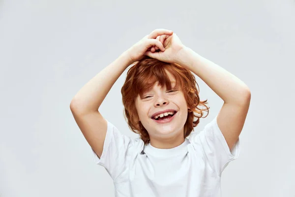 Glad rödhårig pojke händer på huvudet brett leende vit t-shirt — Stockfoto