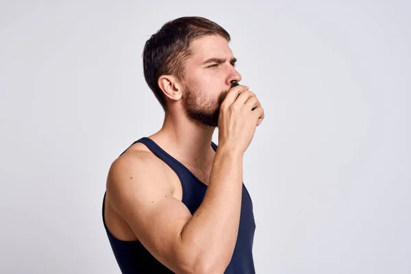 Een man met een machine voor het verwijderen van haar uit een neus in een zwart T-shirt lichte achtergrond lichaamsverzorging — Stockfoto