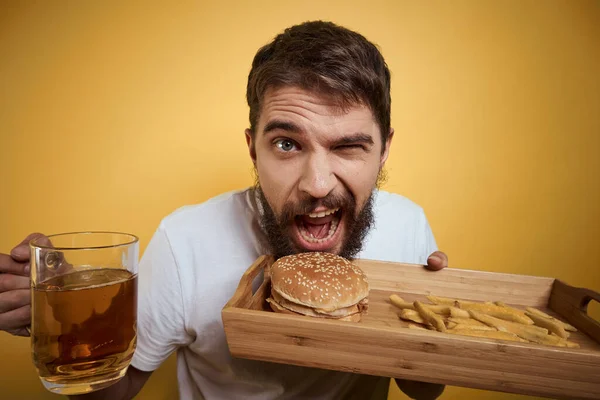 Homem barbudo com caneca de cerveja fast food dieta diversão álcool estilo de vida fundo amarelo — Fotografia de Stock