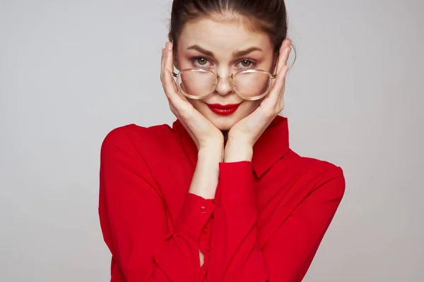 Mujer de moda en una camisa roja sobre un fondo claro emociones divertidas gafas de maquillaje brillantes aspecto atractivo — Foto de Stock