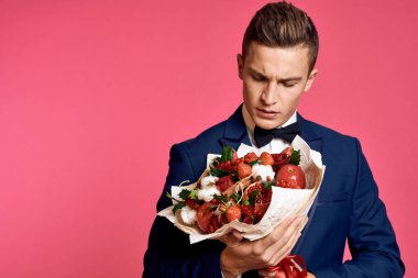 Çiçek buketi ve pembe arka planda papyonlu romantik bir adam.