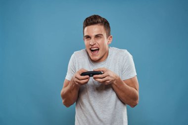 Elinde joystickli bir adam eğlence teknolojisi video oyunları mavi arka plan beyaz tişört