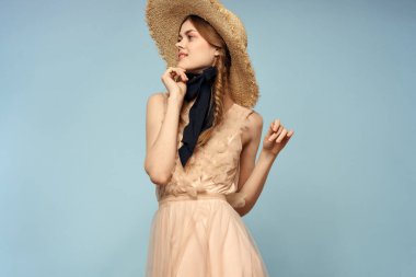 Mavi arka planda pembe elbiseli bir kız elleriyle romantik modeller yapıyor.