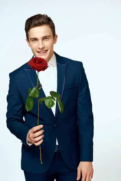 Ein Mann im Anzug mit einer Rose in der Hand ein Geschenk Datum Licht Hintergrund — Stockfoto