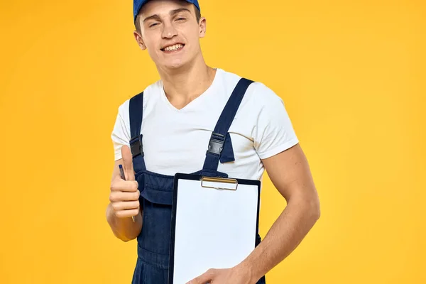 Man in het werken uniforme documenten weergave van diensten bezorgdienst gele achtergrond — Stockfoto