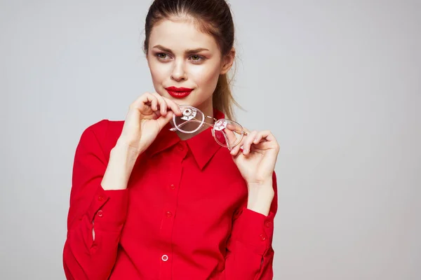 Modieuze vrouw in een rood shirt op een lichte achtergrond leuke emoties heldere make-up bril aantrekkelijk uiterlijk — Stockfoto