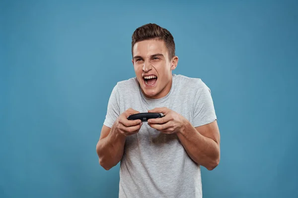 Ein Mann mit einem Steuerknüppel in der Hand Unterhaltung Freizeittechnologie Videospiele blauer Hintergrund weißes T-Shirt — Stockfoto