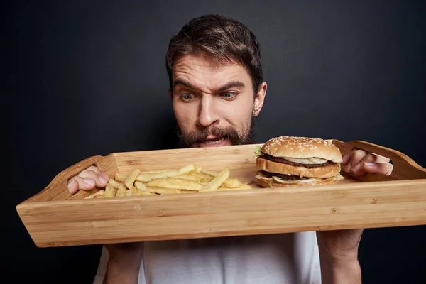 Emotionaler Mann mit Holzpalette Fast Food Hamburger Pommes Frites Essen Food Lifestyle dunkler Hintergrund — Stockfoto