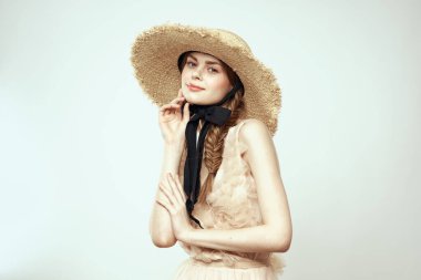 Siyah kurdeleli, saman şapkalı ve açık renk arka planda giyinmiş güzel bir kız.