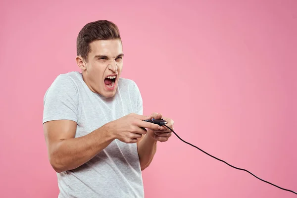 Hombre alegre con joystick alambre tecnología entretenimiento estilo de vida rosa fondo —  Fotos de Stock