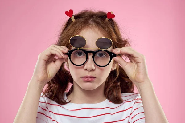 Fille gaie avec des lunettes de soleil pigtails rayé t-shirt style de vie fond rose — Photo