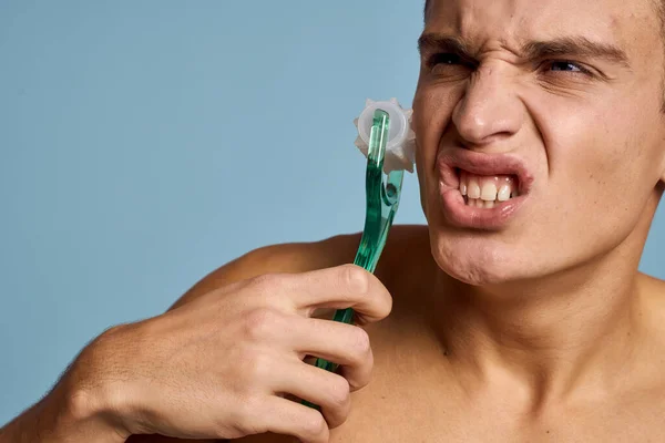 Hombre desnudo con un instrumento de masaje en la mano sobre un fondo azul emociones boca abierta modelo — Foto de Stock