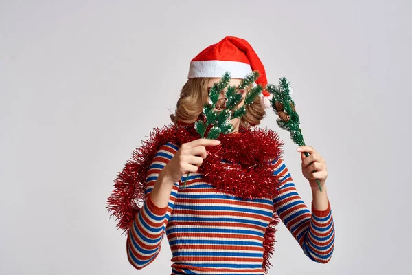 Woman with Christmas-tree branches and in a red cap on a light background New Year — Stock Photo, Image