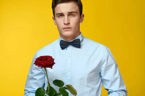 Portrait of a man with a red rose on a yellow background and a light shirt bow tie gentleman — Stock Photo, Image