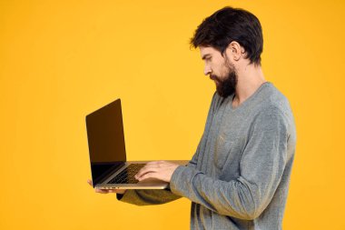 Bilgisayarlı, kablosuz teknolojili internet yaşam tarzı olan adam sarı renkli, izole bir arka plan.