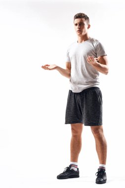 Hafif bir geçmişi olan atletik bir adam tam boy ve koşu şortu spor ayakkabısı tişörtü giyiyor.