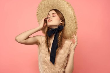 Şapkalı ve siyah kurdeleli güzel bir kadın. Pembe arka plan modeli.